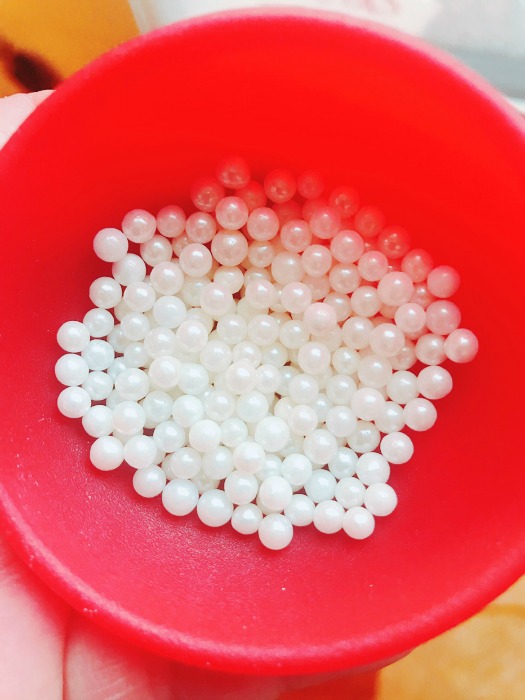 Red bowl with different sizes of white pearls that are made from sugar