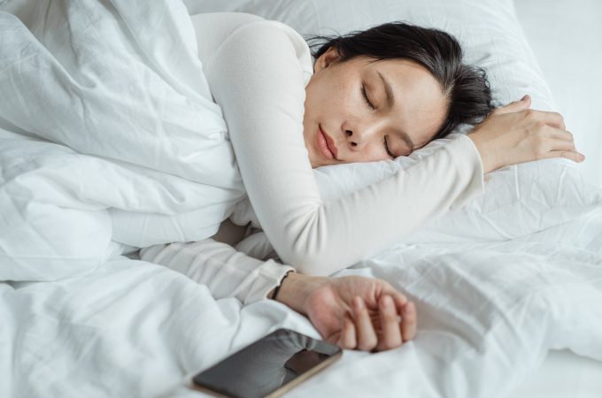 woman sleeping on bed near smartphone